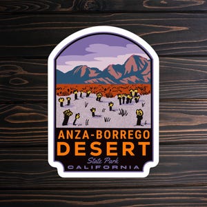May include: A sticker with a colorful illustration of a desert landscape with mountains, a purple sky, and yellow flowers. The text "ANZA-BORREGO DESERT State Park CALIFORNIA" is printed on the sticker.