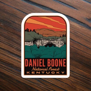 May include: A vintage-style sticker featuring a scenic view of a natural archway in a forest with a red sunset sky. The text reads "Daniel Boone National Forest Kentucky".