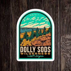 May include: A sticker with a scenic view of a forest with a blue sky and clouds. The text reads "DOLLY SODS WILDERNESS West Virginia".