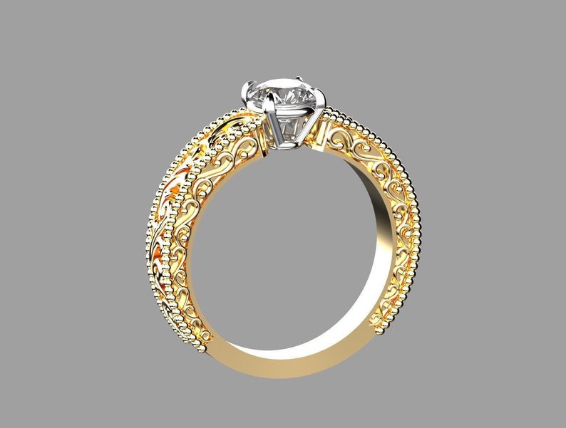 May include: A gold ring with a large, clear gemstone. The band features intricate filigree and beaded detailing. The ring is set against a gray background, highlighting its ornate design and the brilliance of the central stone.