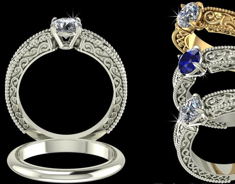 May include: A collection of ornate engagement rings with intricate filigree detailing. The rings feature a variety of gemstones, including a clear diamond and a blue sapphire, set in gold and silver bands. The rings are displayed against a black background.