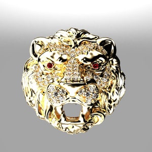 May include: A gold lion head pendant with red gemstone eyes and a detailed design. The pendant is covered in small, clear stones.