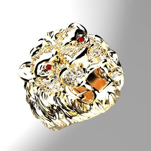 May include: A gold lion head ring with red ruby eyes and a detailed design. The ring is set with clear diamonds.