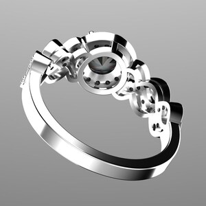 May include: A silver ring with a large round center stone surrounded by smaller stones. The ring has a delicate band and is set with multiple smaller stones.