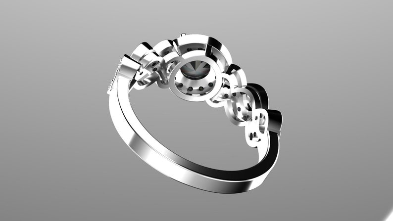 May include: A silver ring with a large round center stone surrounded by smaller stones. The ring has a delicate band and is set with multiple smaller stones.