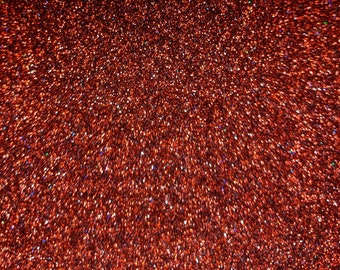 Op de afbeelding: Een close-up van rode glitter met een lichte iriserende glans. De glitter is dicht opeengepakt en creëert een sprankelend effect.
