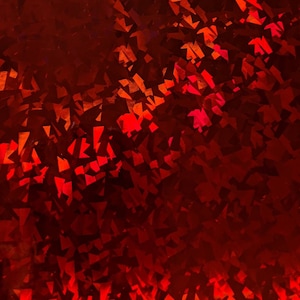 May include: Red iridescent fabric with a textured, geometric pattern. The fabric has a shimmering, holographic effect.