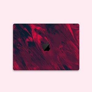 May include: A red and black abstract design laptop skin with a black Apple logo.