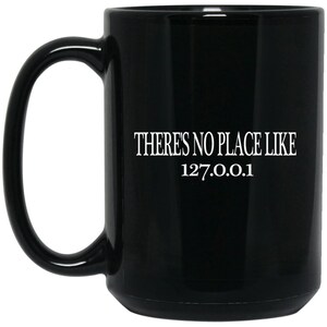 Pode incluir: Caneca de café de cerâmica preta com uma inscrição branca que diz "Não há lugar como 127.0.0.1".