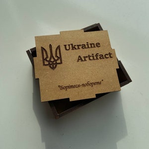 May include: A wooden box with a brown lid featuring a Ukrainian coat of arms, the words "Ukraine Artifact" and the text "Боримесь-побореме".