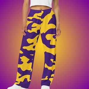 May include: Purple and yellow patterned pants. The pants feature a repeating abstract design in a vibrant color combination. The pants are made of a soft, comfortable material.