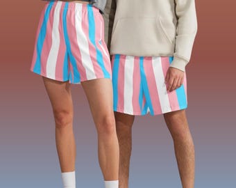 以下が含まれることがあります： ピンク、白、水色のストライプ柄のショートパンツが2組。 ショーツは伸縮性のあるウエストバンドで、2人の人が着用しています。 背景は茶色と青のグラデーションです。