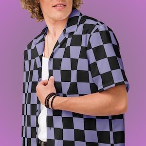 May include: A short-sleeved button-down shirt with a black and lavender checkerboard pattern. The shirt has a classic collar and is worn over a white undershirt. The background is a solid purple color.
