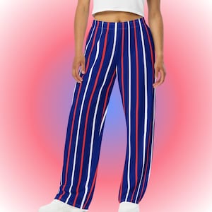 May include: Wide-leg pants with vertical stripes in navy blue, red, and white. The pants are worn by a person and are made of a lightweight fabric. The background is a gradient of pink and red.