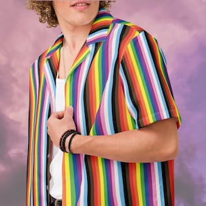 May include: A short-sleeved button-down shirt with vertical stripes in a rainbow of colors, including red, orange, yellow, green, blue, brown, and purple. The shirt is worn over a white undershirt.