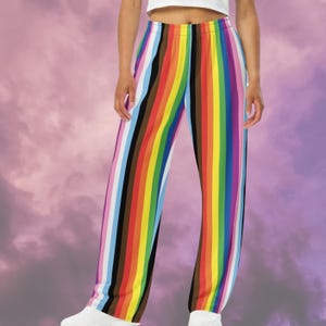Op de afbeelding: Broek met veelkleurige strepen en verticale regenboogstrepen. De strepen omvatten rood, oranje, geel, groen, blauw, paars, zwart, bruin en wit. De broek heeft een wijd beenontwerp en is gemaakt van een zacht materiaal.