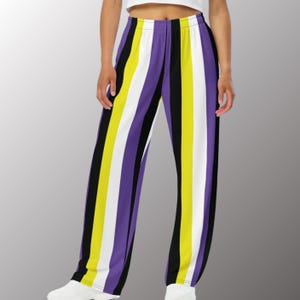 May include: Non-binary pride flag-colored pants with vertical stripes in yellow, white, purple, and black. The pants have a relaxed fit and a comfortable elastic waistband. The design is bold and eye-catching, perfect for expressing identity.