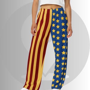 May include: Loose-fitting pants with a split design. One leg features vertical stripes in yellow and maroon, while the other has a blue background with yellow stars. The pants are made of a soft, flowing fabric.