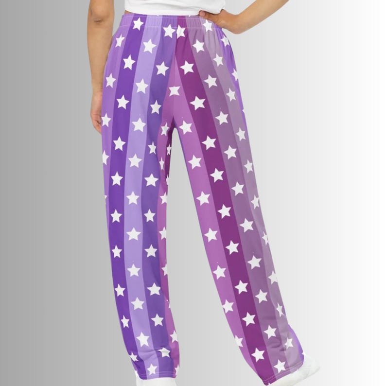Puede incluir: Pantalones a rayas moradas y lavanda con patrones de estrellas blancas. Los pantalones tienen un corte holgado y est&aacute;n hechos de un material suave. El dise&ntilde;o presenta rayas verticales en tonos morados y lavanda, con estrellas blancas espaciadas.