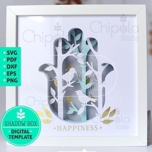 Könnte beinhalten: Weißer Rahmen mit einem Papierschnitt-Design einer Hamsa-Hand mit Bäumen, Vögeln und Blättern. Das Design ist in Blautönen, Grün und Gold gehalten. Der Text "HAPPINESS" ist unter dem Design gedruckt. Der Text "Chipolla Studio" ist in der oberen rechten und unteren rechten Ecke des Rahmens gedruckt.