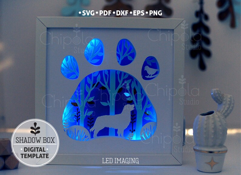 May include: A white shadow box with a blue LED light shining through a cut-out design of a dog paw print with a dog and trees inside. The text "LED IMAGING" is printed below the design. The text "SHADOW BOX &bull; DIGITAL &bull; TEMPLATE" is printed on the left side of the image.