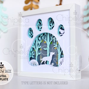 May include: A white shadow box with a blue paw print design. The paw print is cut out and the inside of the paw print is a forest scene with a dog silhouette. The text "TYPE LETTERS IS NOT INCLUDED" is at the bottom of the box.