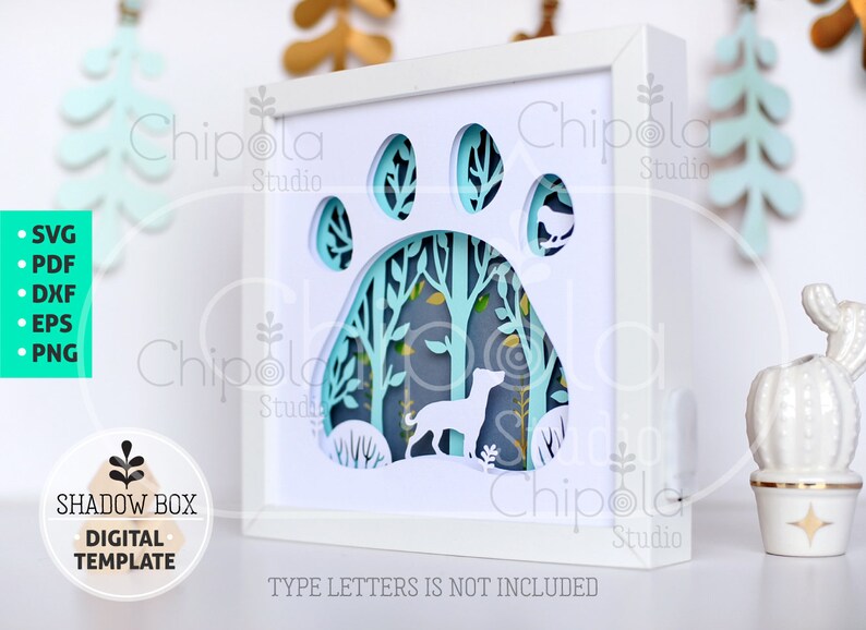 May include: A white shadow box with a blue paw print design. The paw print is cut out and the inside of the paw print is a forest scene with a dog silhouette. The text "TYPE LETTERS IS NOT INCLUDED" is at the bottom of the box.