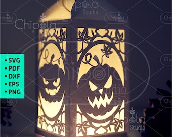 Puede incluir: Una linterna de papel blanca con un diseño recortado de un árbol con calabazas y hojas. La linterna está iluminada desde adentro, proyectando un brillo cálido. La linterna está sobre una superficie oscura con una piña en el fondo. El texto "Chipola Studio" es visible en la parte inferior de la imagen.