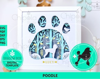 May include: A white framed shadow box featuring a poodle silhouette within a paw print design. The layered paper art includes trees and the name "LUCY". Additional graphics include a poodle silhouette and the word "POODLE".