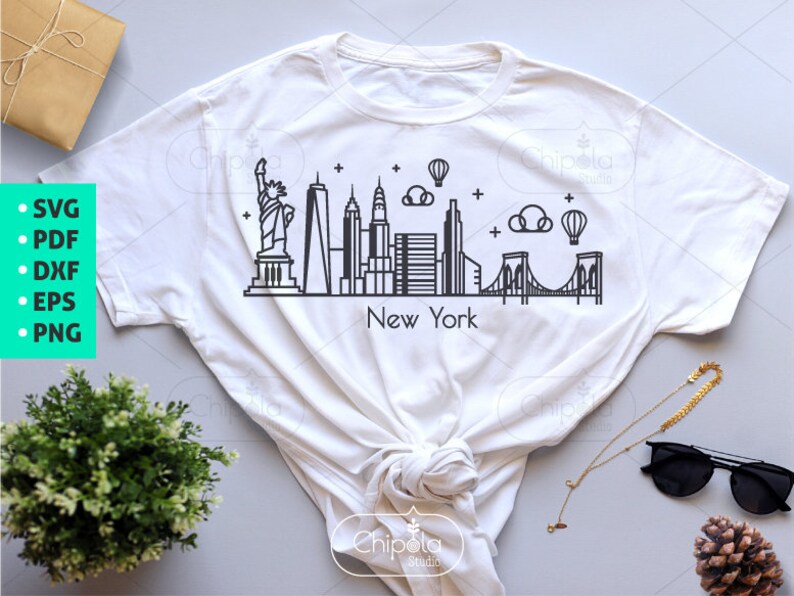 May include: A white t-shirt with a black outline of the New York City skyline, including the Statue of Liberty, the Empire State Building, and the Brooklyn Bridge. The text "New York" is printed below the skyline.