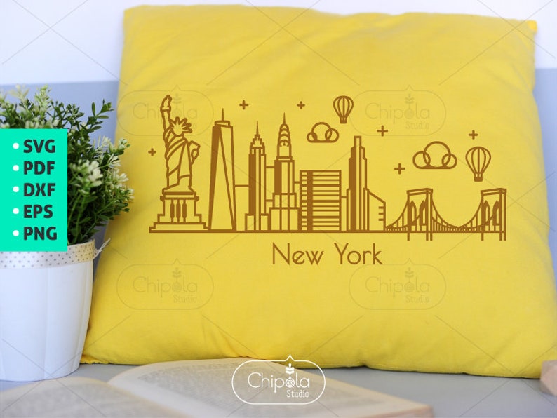 May include: A yellow pillow with a brown outline of the New York City skyline, including the Statue of Liberty, the Empire State Building, and the Brooklyn Bridge. The text "New York" is below the skyline.
