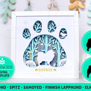May include: A white shadow box with a blue paw print design and a silhouette of a dog inside. The paw print has a forest scene with trees and leaves. The dog is a Samoyed breed and the name "Sophie" is written below the dog. The box is for a digital template.