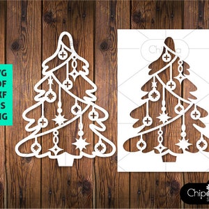 May include: White cutout design of a Christmas tree with baubles and stars. The design is on a wood background.