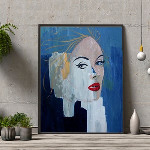 Puede incluir: Pintura abstracta de la cara de una mujer con pintura azul, blanca y dorada. La mujer tiene labios rojos y ojos azules. La pintura está enmarcada en negro.