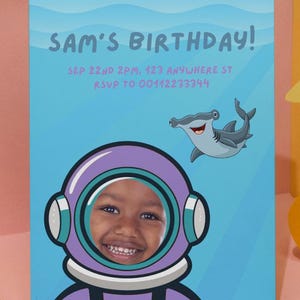 May include: A blue and purple birthday invitation with a cartoon hammerhead shark and a child's face in a purple astronaut helmet. The text reads "Sam's Birthday!" and "Sep 22nd 2PM, 123 Anywhere St RSVP to 00412233344".