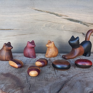 May include: A set of wooden animal figurines, including a bear, two foxes, and a cat, with a variety of wood grain patterns. The figurines are arranged on a wooden surface with five wooden discs.