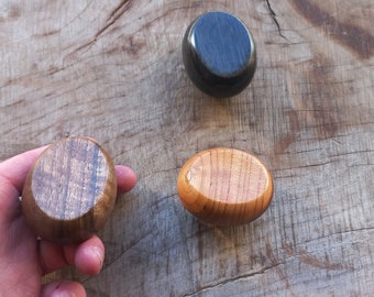 May include: Three wooden knobs, one black, one brown, and one light brown. The knobs are round and have a smooth finish.