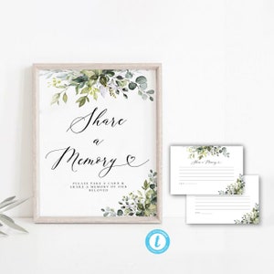 Puede incluir: Un cartel imprimible con un diseño floral verde y blanco que dice "Compartir un recuerdo &" con instrucciones para tomar una tarjeta y compartir un recuerdo de un ser querido. El cartel está enmarcado en un marco de madera claro.