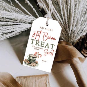 Puede incluir: Etiqueta de regalo blanca con texto rojo y verde que dice "Just a little Hot Cocoa Treat for someone extra Sweet". La etiqueta presenta una ilustración de acuarela de una taza de chocolate caliente con malvaviscos, un bastón de caramelo y una galleta de jengibre.