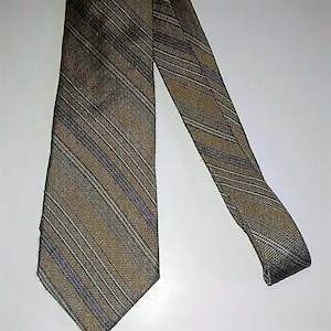 Puede incluir: Una corbata a rayas con rayas marrones y grises. La corbata está hecha de tejido tejido.