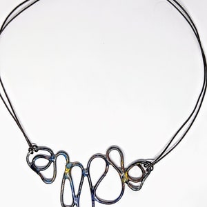 May include: A black necklace with a copper clasp and a blue and yellow abstract metal pendant.