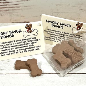 May include: Two cards with the text "Savory Saver Bones" and a cartoon dog holding a bone. The text explains how to keep the bones fresh and clean. A small white mesh bag contains several brown bone-shaped treats.