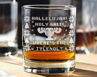 May include: A clear glass tumbler with a white design featuring a moose and the text "Hallelujah! Holy Shit! Where's the Tylenol?"