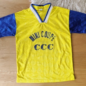 May include: Yellow and blue soccer jersey with the text "MINI COUPE CCC" printed on the front.