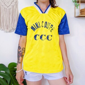 May include: Yellow and blue short-sleeved jersey with the text "MINI COUPE CCC" printed on the front.