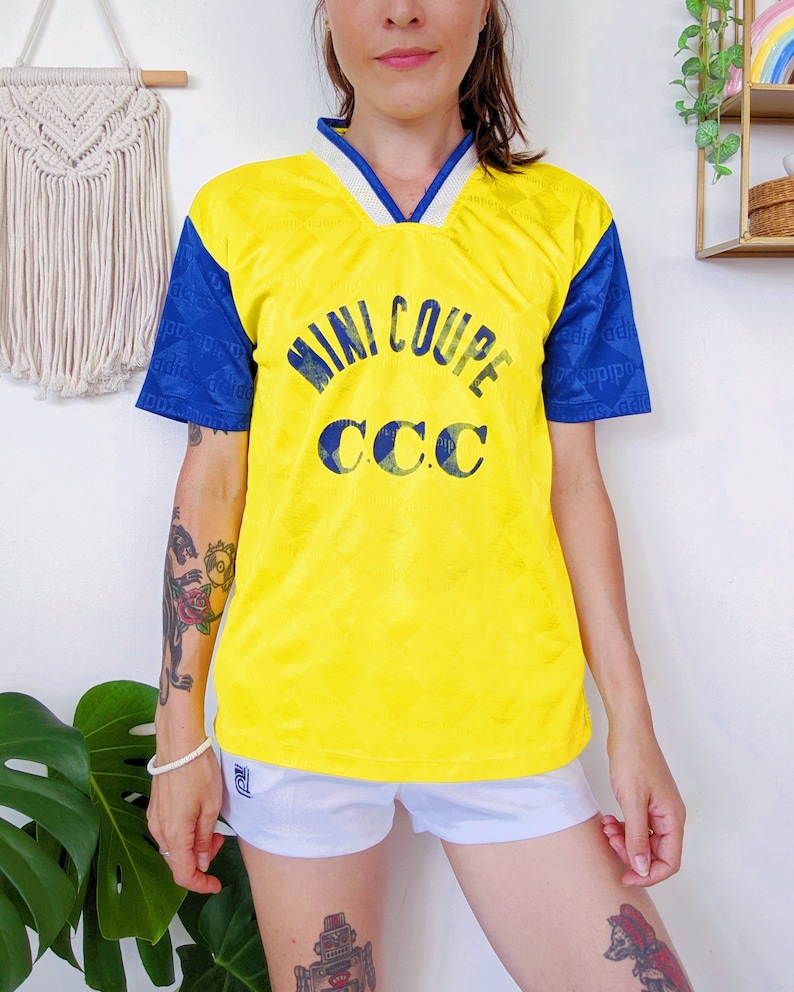 May include: Yellow and blue short-sleeved jersey with the text "MINI COUPE CCC" printed on the front.
