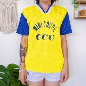 May include: Yellow and blue soccer jersey with the text "MINI COUPE CCC" printed on the front.