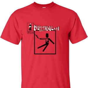 Puede incluir: Camiseta roja con un gráfico en blanco y negro de una figura de palo siendo electrocutada. El texto "Buckethead Land" está impreso en blanco sobre el gráfico. Los números "51 134" están impresos en blanco debajo del gráfico.