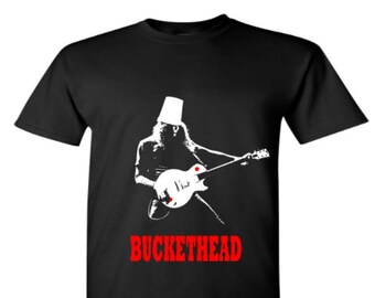 May include: Black t-shirt with a white silhouette of a musician wearing a bucket on their head and playing a guitar. The text "BUCKETHEAD" is printed in red below the image.