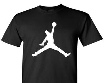 May include: Black t-shirt with a white silhouette of a basketball player jumping and holding a basketball.
